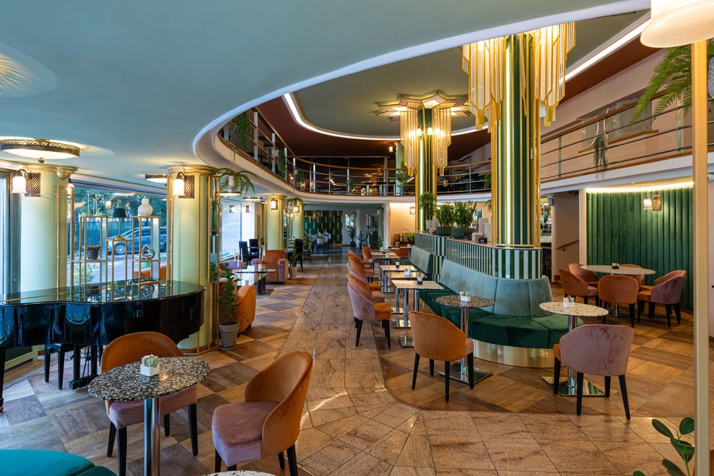 A Dunapark Kávéház világos, elegáns vendégtere zongorával és art deco építészeti részletekkel